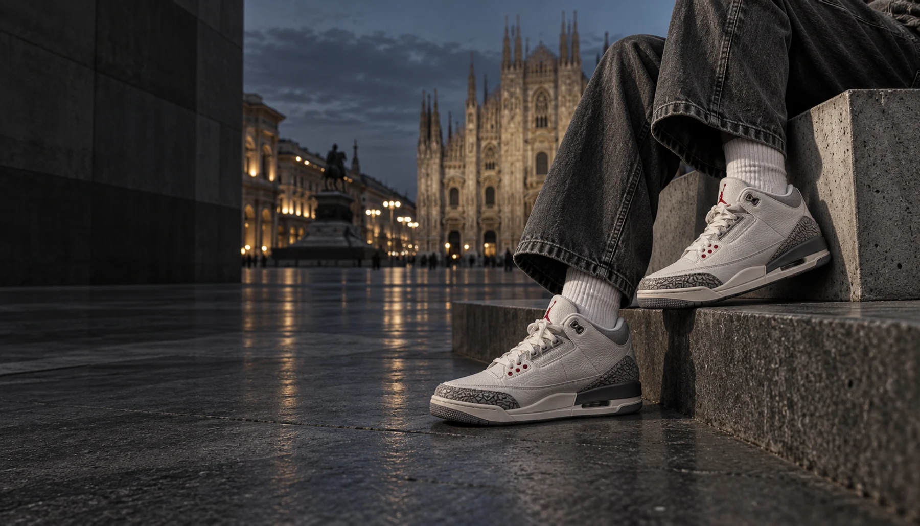 Sneaker bianche e grigie, denim e architettura in cemento in una piazza italiana