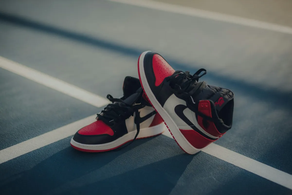 Sneaker rosse, nere e bianche su un campo da basket